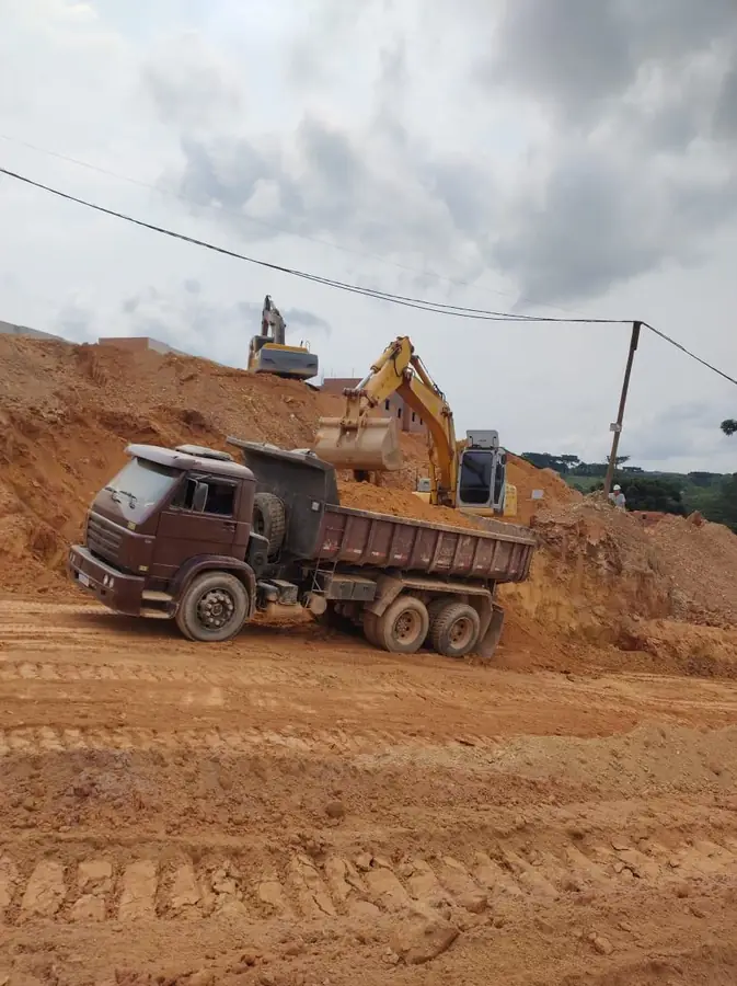 Escavadeira carregando caminhão caçamba em corte de terreno em Curitiba