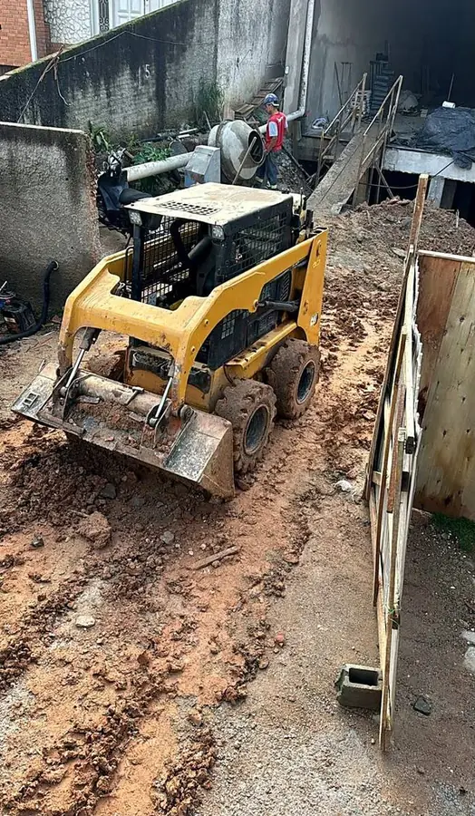 Minicarregadeira CAT espalhando terra em preparação de terreno residencial